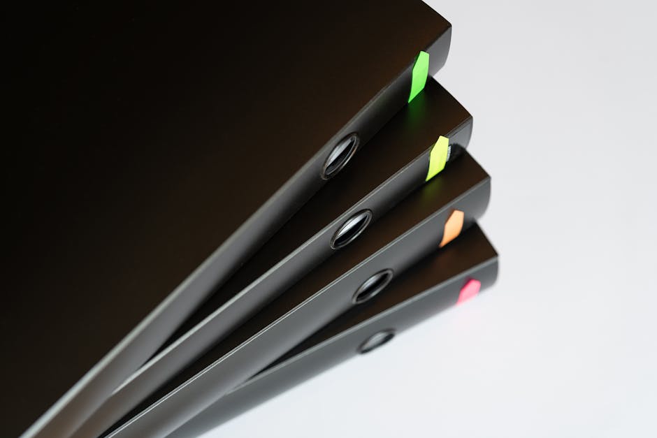 A neat stack of black office binders with colorful tabs, symbolizing organization and management.